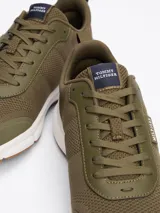 Zapatillas de running Tommy Hilfiger color verde oliva, con exterior de punto y poliéster, interior de poliéster, plantilla extraíble de goma termoplástica reciclada, suela de EVA dentada y trabilla para calzar.