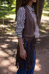 Chaleco de estilo boho confeccionado en cuero sintético color marrón, con flecos largos en el ruedo y detalle de tachas metálicas a lo largo de los bordes frontales.