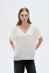 Blusa blanca de poliéster de corte holgado, con escote en V y mangas cortas.