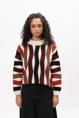 Buzo de tejido de punto con diseño de rayas verticales onduladas en tonos tierra, negro y crema. Presenta cuello redondo, mangas largas y corte holgado.