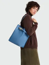 Bolso tipo shopping bag de cuero azul, con diseño estructurado, asa de hombro fija y detalle de cierre metálico dorado en la parte superior.