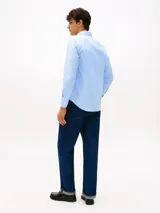 Camisa de manga larga Tommy Hilfiger en color celeste, con cuello clásico, cierre frontal de botones y logo de la marca bordado en el pecho. Presenta un corte regular y tejido técnico flexible.