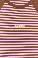 Camiseta de corte slim fit con diseño de rayas horizontales en tonos marrón y rosado. Presenta mangas cortas tipo ranglán en color marrón sólido, cuello redondo y un pequeño texto bordado en el centro del pecho.