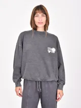 Buzo gris oscuro con efecto acid wash, cuello redondo, mangas largas y pequeño estampado blanco en el pecho con texto y motivos florales.