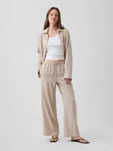 Pantalón wide leg de lino con rayas verticales en tonos beige y blanco, con cintura elástica y cordón ajustable.