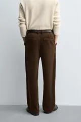 Pantalón de corte wide fit confeccionado en pana de algodón color marrón oscuro. Presenta bolsillos frontales, bolsillos traseros de vivo con botón y cierre frontal con cremallera y botón.