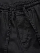 Pantalón de jogging negro de pierna ancha, tiro medio alto y corte amplio. Con cintura elástica ajustable con cordón, bolsillos delanteros y traseros, y puños doblados.