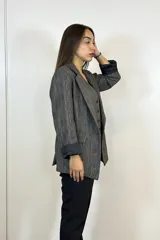 Blazer de corte entallado en color gris con textura jaspeada, solapas clásicas, bolsillos laterales y mangas con vuelta en contraste negro.