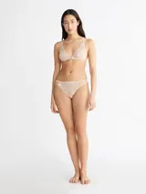 Brasier Calvin Klein de encaje semitransparente con diseño floral, copas triangulares sin forro y cierre frontal con broche metálico.