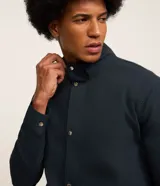 Campera bomber azul marino para hombre, confeccionada en sarga de algodón sostenible. Tiene cuello alto, cierre abotonado, bolsillos cargo con solapa y puños elásticos.