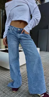 Jean de tiro bajo con corte wide leg y diseño de cinco bolsillos. Presenta un lavado clásico en tono azul medio con efecto desgastado.