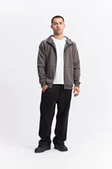 Campera con capucha y cierre frontal, color beige, con detalles de costuras y cierres en negro. Presenta mangas largas con puños acanalados y logo pequeño en el pecho.