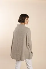 Capa de lana fina sin teñir, con estampado de espiga en tonos marrones y beige. Presenta cuello alto, mangas amplias, bolsillos laterales y pinzas en la parte delantera.
