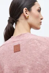 Ruana de tejido de punto color rosa melange, sin mangas y con cuello redondo.