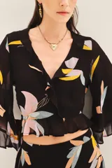 Camisa corta tipo crop top de viscosa georgette con estampado floral. Presenta mangas amplias con volados y detalle de volado en la cintura. Incluye forrería a tono.