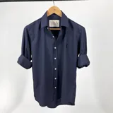Camisa de algodón a cuadrillé chico azul marino, con cuello italiano y mangas largas con puño abotonado.