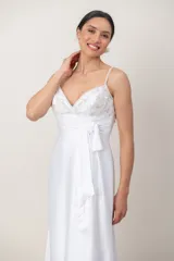 Vestido largo de novia blanco con corte imperio y tirantes finos. Presenta el cuerpo superior bordado a mano con abalorios y pedrería, faja drapeada con lazo lateral y falda fluida con cola.
