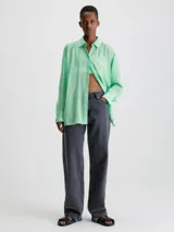 Camisa verde menta de rayón arrugado, corte regular, cuello en punta, manga larga con puños abotonados y espalda dividida con detalle anudado.