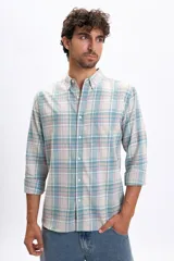 Camisa de manga larga con estampado de cuadros en tonos crudo, verde agua y lila. Presenta cuello camisero con botones, cierre frontal abotonado y un bolsillo en el pecho.