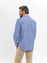 Camisa de manga larga con estampado de rayas verticales en azul y blanco, cuello clásico y cierre frontal de botones.