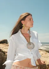 Collar de cadena de eslabones metálicos dorados con un dije central de piedra ágata natural en forma circular.