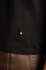 Remera de algodón peinado color negro, con mangas cortas de broderie con diseño calado y terminación festoneada. Presenta un corte oversize y cuello redondo.
