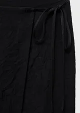 Falda midi tiro medio de color negro, con diseño cruzado y tajo delantero.