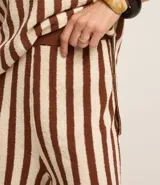 Pantalón de punto color crema con rayas verticales marrones, de corte recto y cintura alta con elástico.