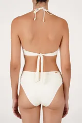Malla enteriza color beige con cuello halter alto, tirantes para anudar al cuello, detalle de bordado con cuentas en el pecho y fruncidos en los laterales.