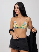 Top de bikini triangular con estampado tropical de flores azules y hojas verdes sobre fondo naranja y crema. Cuenta con tiras finas para atar en el cuello y la espalda.