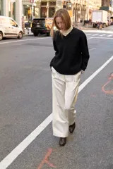 Jersey de punto negro, con cuello en V (pico) y manga larga, acabado en rib en puños, cuello y bajo.