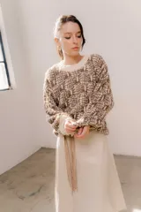 Buzo de tejido grueso con diseño artesanal bicolor en tonos marrón y crema. Presenta cuello redondo y terminaciones en rib en puños y cintura, con un calce relajado.