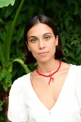 Collar doble compuesto por una gargantilla de cuentas pequeñas en tonos rojo y blanco, y un collar de cuentas facetadas rojas con un dije central en forma de rama de coral.