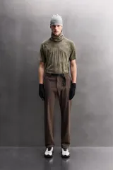 Pantalón de hombre color marrón oscuro, corte regular fit, confeccionado en tejido técnico compacto elástico. Presenta cintura ajustable con cinturón negro a contraste, bolsillos frontales, bolsillo trasero con cierre y bolsillo cargo con cierre en la pernera.