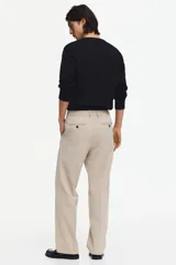 Pantalón de vestir color beige, de corte relajado, con bolsillos laterales y traseros, y raya marcada en las piernas.