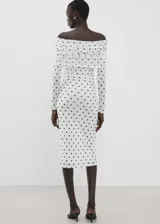 Vestido midi entallado de color blanco con estampado de lunares negros, escote palabra de honor con solapa drapeada y manga larga.