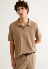 Chomba de manga corta en color beige, con cuello camisero y cierre frontal parcial.