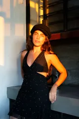 Vestido corto negro con estampado de plumas doradas, escote en V, breteles finos cruzados en la espalda, cut-outs laterales y volado en el ruedo.