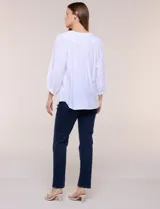 Blusa blanca de rayón y poliéster con textura, escote en V y delicados bordados al tono sobre el canesú. Cuenta con mangas raglán tres cuartos abullonadas con puños elastizados y diseño holgado.