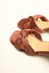 Sandalia de tacón cuadrado medio, confeccionada en terciopelo negro. Presenta un diseño de tiras cruzadas con nudo en la parte delantera y una tira ajustable con hebilla en el tobillo.