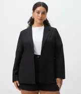 Blazer alargado en crepé negro de corte holgado, con solapas clásicas, frente abierto sin botones y bolsillos delanteros.