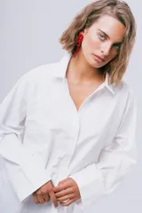 Camisa blanca de manga larga con cuello camisero, cierre frontal con botones y puños anchos.