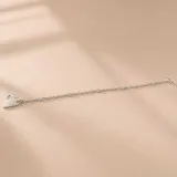 Pulsera de plata con cierre tipo T-bar, dijes de circonias engastadas a lo largo de la cadena y un dije colgante en forma de corazón.