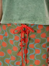 Short holgado de cintura alta con pretina integrada, cordón ajustable delantero y estampado geométrico en tonos rojos y beige.
