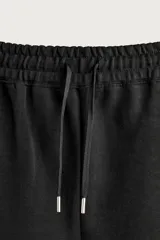 Bermuda estilo jogger de ajuste relajado, color negro, confeccionada en tejido interlock de algodón. Cuenta con cintura elástica ajustable mediante cordón, bolsillos delanteros tipo vivo y diseño liso.
