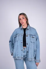 Campera oversize de denim de algodón en color celeste, con diseño de hombros caídos, bolsillos con solapa en el pecho y cierre frontal con botones.