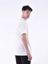 Remera blanca a rayas horizontales grises, con cuello redondo abotonado y bolsillo en el pecho.