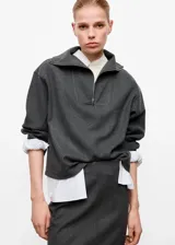 Jersey de cuello alto con cierre de cremallera corta y manga larga, de diseño amplio y color gris oscuro.