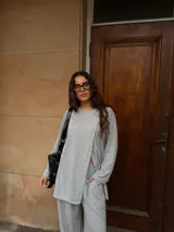 Conjunto de dos piezas color gris melange, confeccionado en tela de lanilla, compuesto por un buzo de manga larga con diseño cruzado al frente y un pantalón largo de corte holgado y tiro alto.