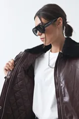 Campera de cuero sintético con acabado satinado, silueta relajada y elástico en la cintura. Presenta cuello con textura de piel sintética, cierre frontal y bolsillos laterales.